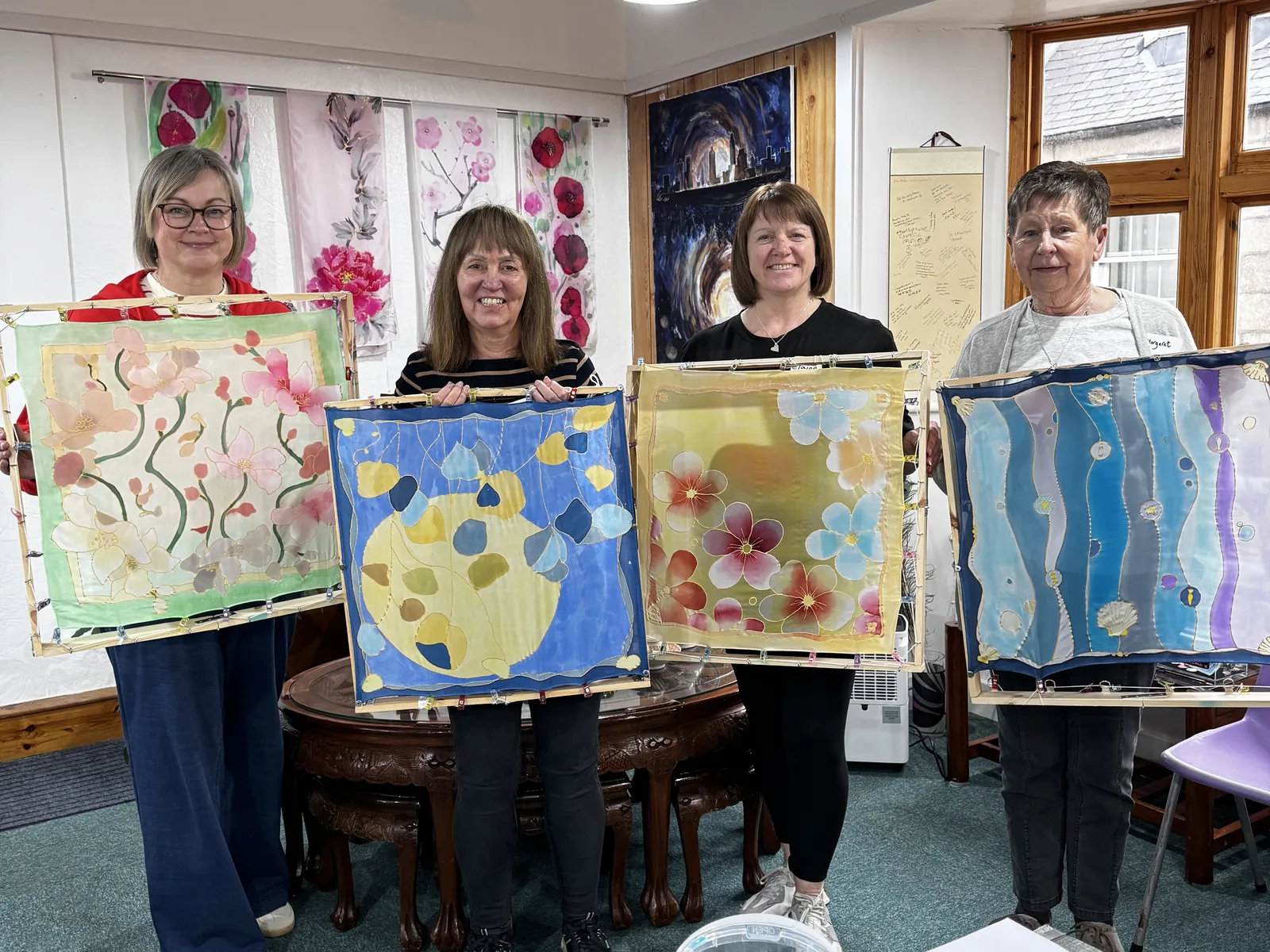 Guests holding finished silk paintings after a guided workshop at Huntly Silk Painting Studio